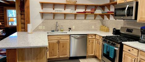 A modern kitchen with wooden cabinets, a stainless steel dishwasher, a gas stove, and a microwave.