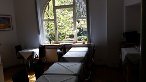 A room with a large arched window, a table with a white tablecloth, and chairs. - Hotel Robert Mayer (Frankfurt)