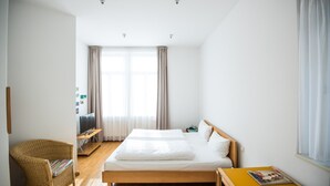A bedroom with a bed, a chair, a desk, and a window. - Hotel Robert Mayer (Frankfurt)