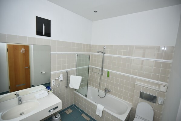 Un baño moderno con lavamanos, espejo, ducha con mampara de cristal, bañera y retrete.