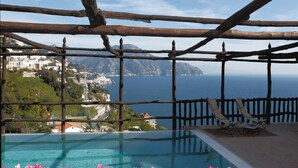 A pool with a view of a coastal town and the sea.