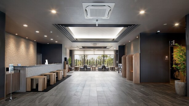 Un'ampia hall con reception, area salotto e grandi finestre che lasciano entrare la luce naturale.