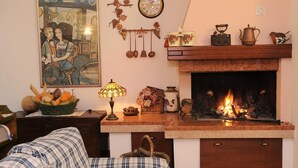 A cozy living room with a fireplace, a painting, a clock, and various decorative items. - Affittacamere Marisa (Valeggio sul Mincio)