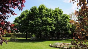 A well-maintained garden with a stone fountain, lush green grass, and a variety of trees. - Affittacamere Marisa (Valeggio sul Mincio)