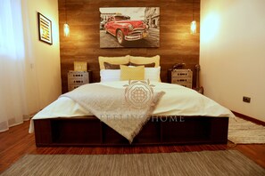 Quarto com cama grande, cabeceira de madeira, duas mesas de cabeceira e uma imagem pendurada na parede de um carro.