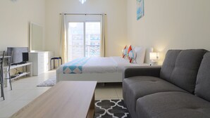 A modern hotel room with a bed, a sofa, a desk, and a television.
