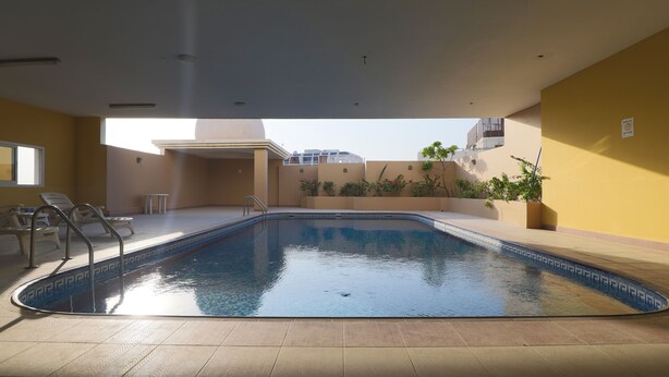An indoor swimming pool with clear water, surrounded by beige walls and a tiled floor.