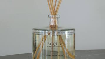 Una botella de vidrio transparente con ramitas de madera insertadas, sobre una superficie oscura.