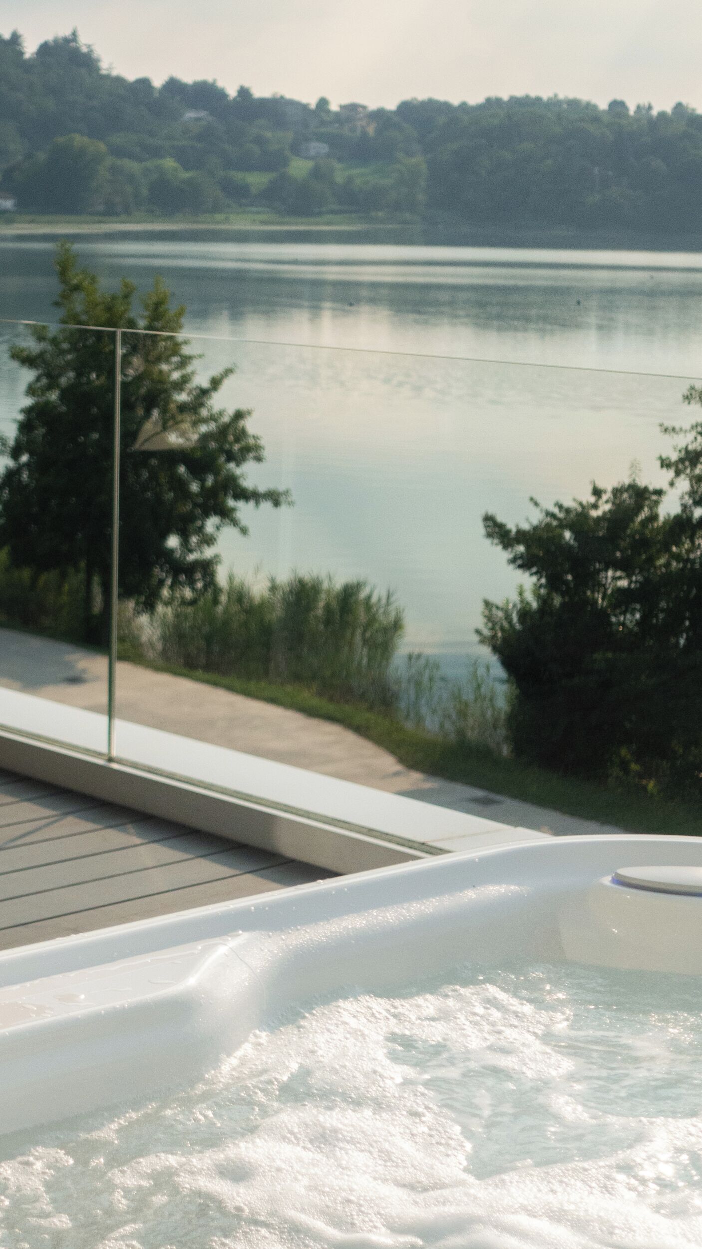 Un bain à remous avec vue sur un lac paisible et des arbres en arrière-plan.