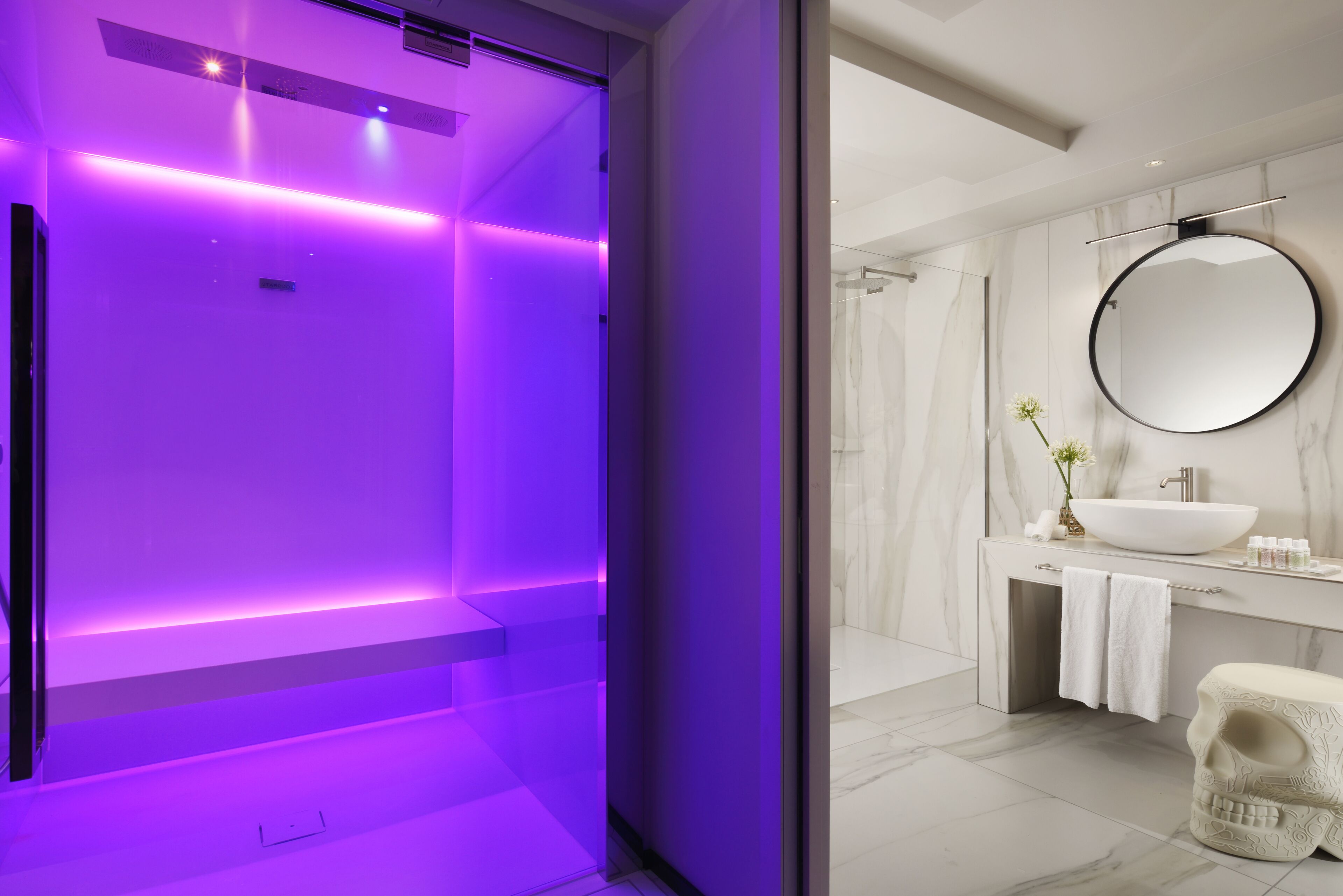 Un bagno moderno con un grande specchio, un lavandino bianco e una parete in marmo.