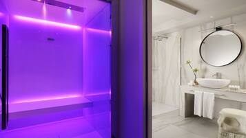 Un bagno moderno con un grande specchio, un lavandino bianco e una parete in marmo.