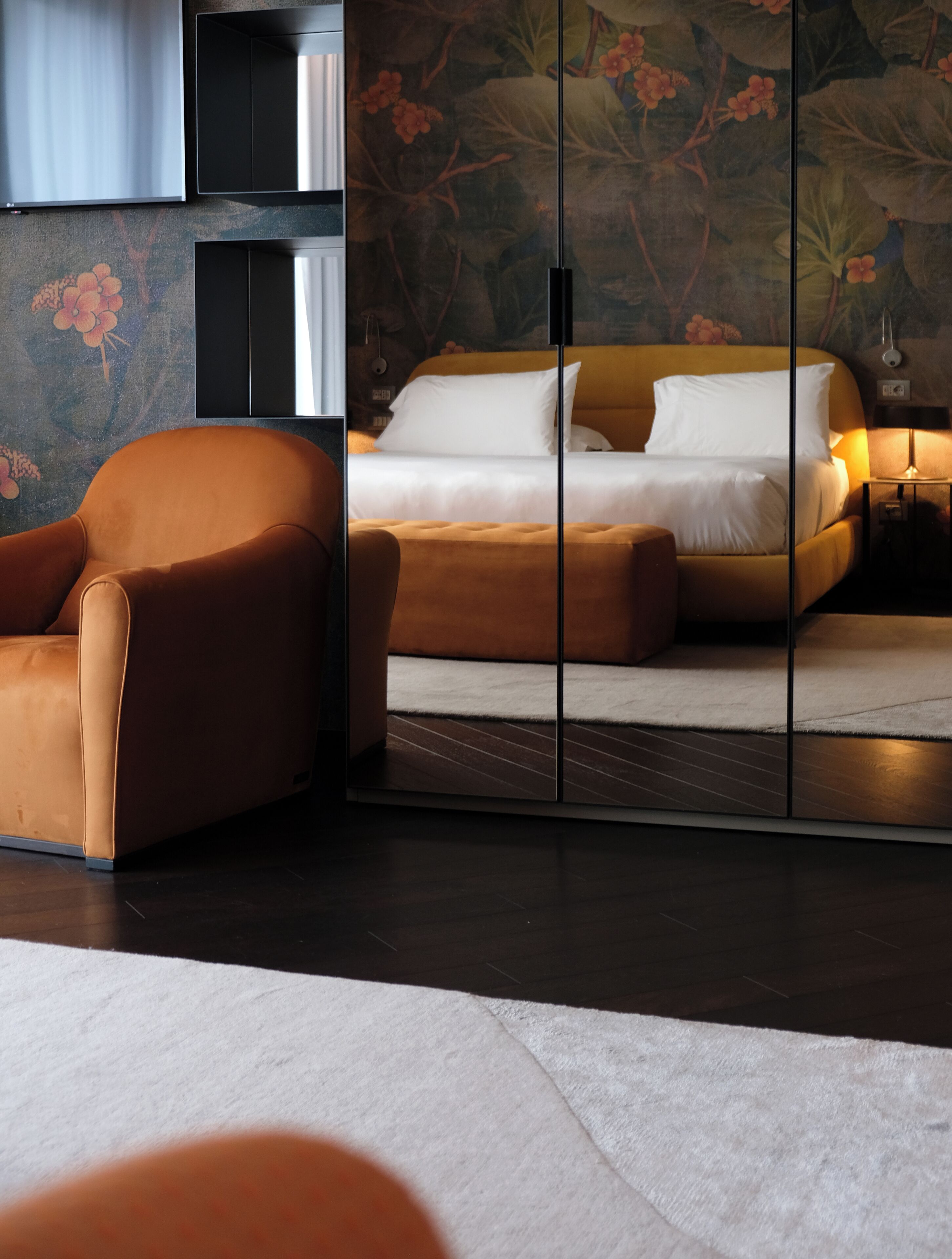 Ein modernes Schlafzimmer mit einer Couch, einem Bett mit weißer Bettwäsche und einer Wandverzierung.