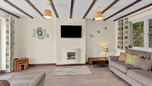 A living room with a fireplace, a television, and a sofa. - Conveniently located to explore all that Cornwall and Devon have to offer (SALTASH)