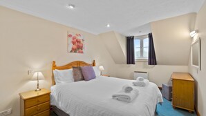 A neatly arranged bedroom with a bed, bedside tables, a dresser, and a painting on the wall. - A spacious 2 bedroom property (SALTASH)