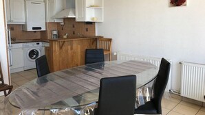 A compact kitchen with a dining area, including a washing machine, a wooden countertop, and a table with chairs. - Duplex T3 for 6, beach nearby, private parking (Le Barcarès)