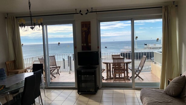 A balcony with a view of the sea, a dining area with chairs and a table, and a sofa. - Duplex T3 for 6, beach nearby, private parking (Le Barcarès)