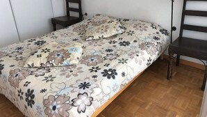 A single bed with a floral bedspread, two bedside tables with lamps, and a wooden chair. - Duplex T3 for 6, beach nearby, private parking (Le Barcarès)