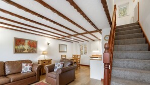 A living room with a wooden staircase, a dining area, and a kitchen. - A very spacious and versatile property suitable for couples, young families and those with an infant (SALTASH)