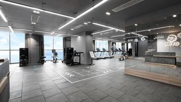 Un gimnasio moderno con equipamiento de ejercicio, ventanas amplias y una zona de recepción.