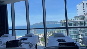 A hotel room with two beds, a large window offering a view of the sea and a cityscape. - The Empyrean Nha Trang (Nha Trang)