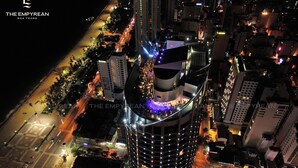 A high-rise hotel with a curved facade, multiple floors, and a rooftop terrace with outdoor seating. - The Empyrean Nha Trang (Nha Trang)
