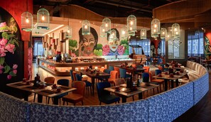 Un restaurante con una zona de asientos curvada, una barra y lámparas colgantes.