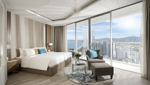 A modern hotel room with a large bed, a sitting area, and a view of the cityscape through floor-to-ceiling windows. - The Empyrean Nha Trang (Nha Trang)