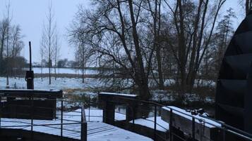 A snow-covered wooden bridge in a park with bare trees and a clear sky.