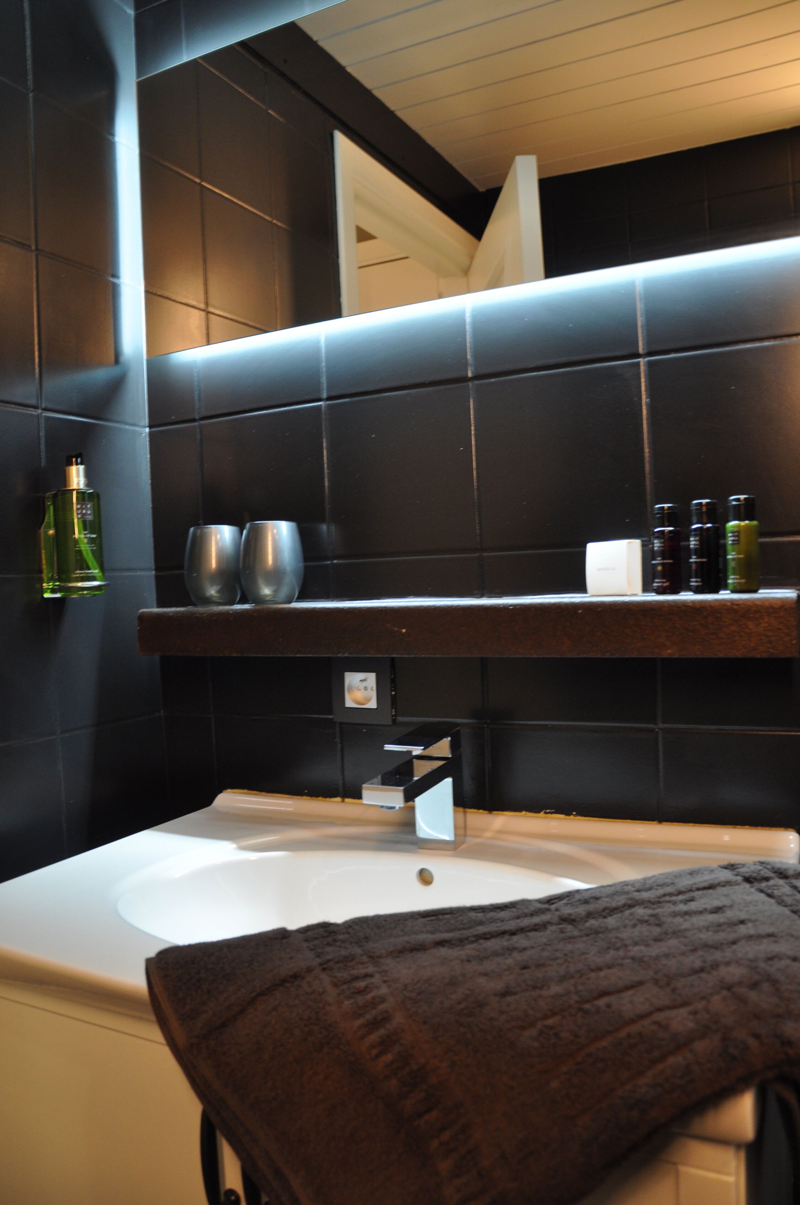 Een badkamer met een bad, een plank met toiletartikelen en een handdoek.