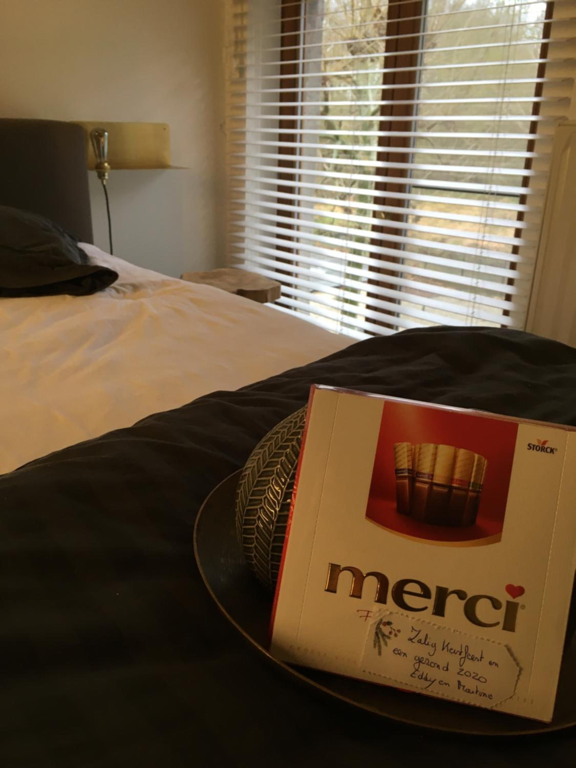 Une chambre d’hôtel avec un lit, une lampe de chevet et une fenêtre avec des stores.
