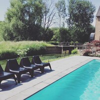 A swimming pool with lounge chairs and a bridge over a water feature.