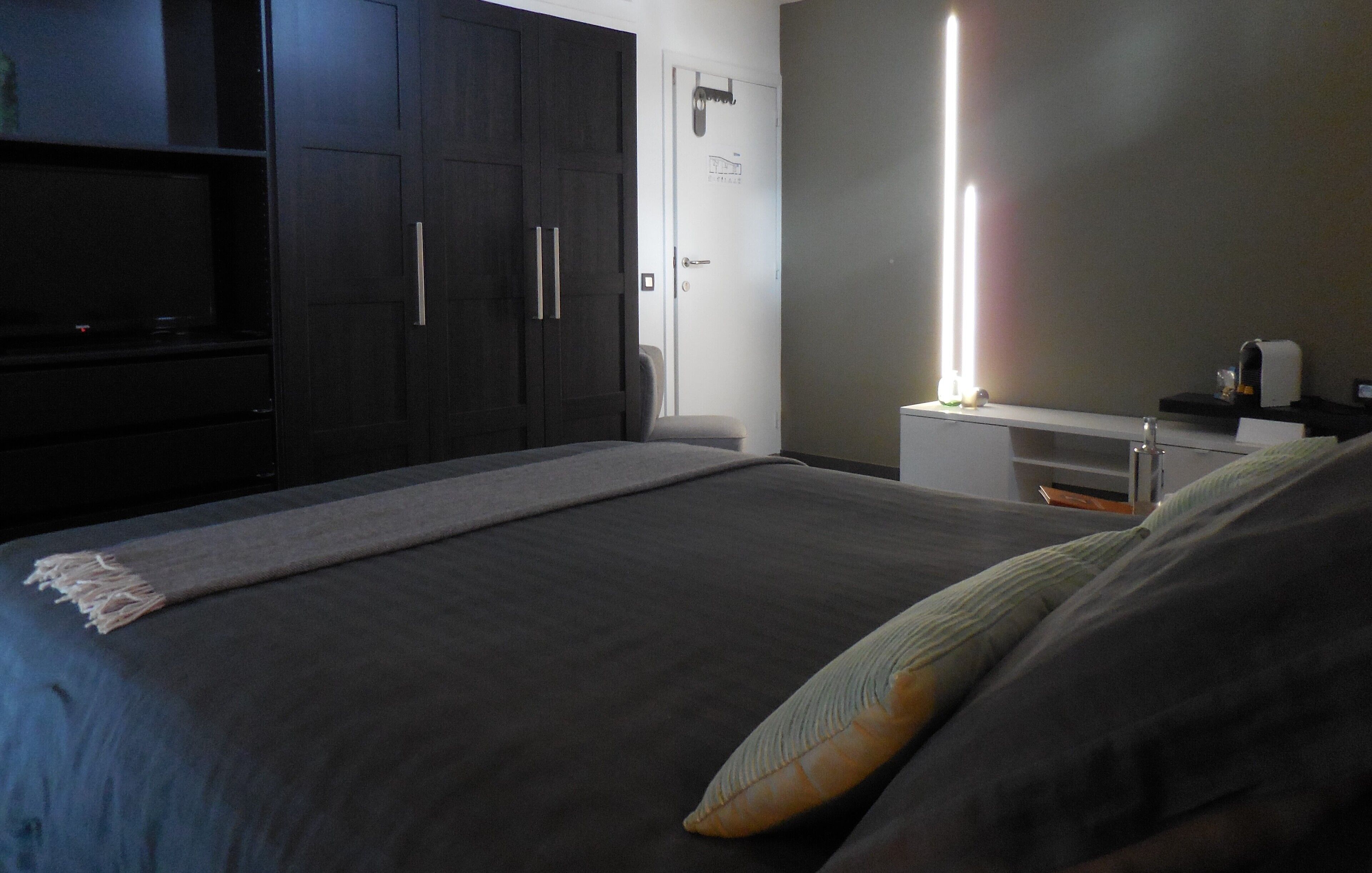 Un dormitorio con una cama grande, un armario de madera oscura y una mesita de noche con lámpara.