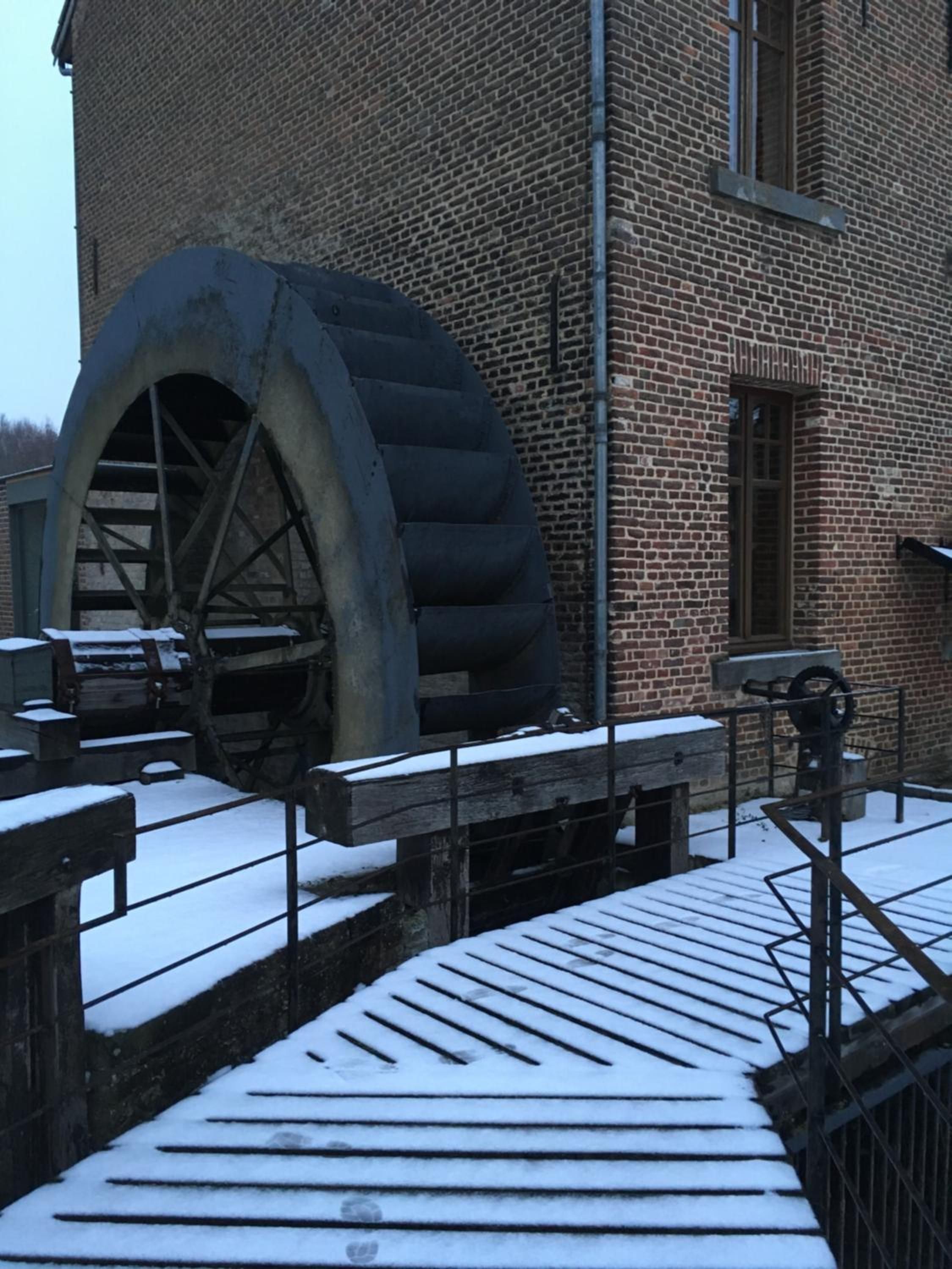 Un bâtiment historique doté d’une grande roue à eau et de murs en briques.