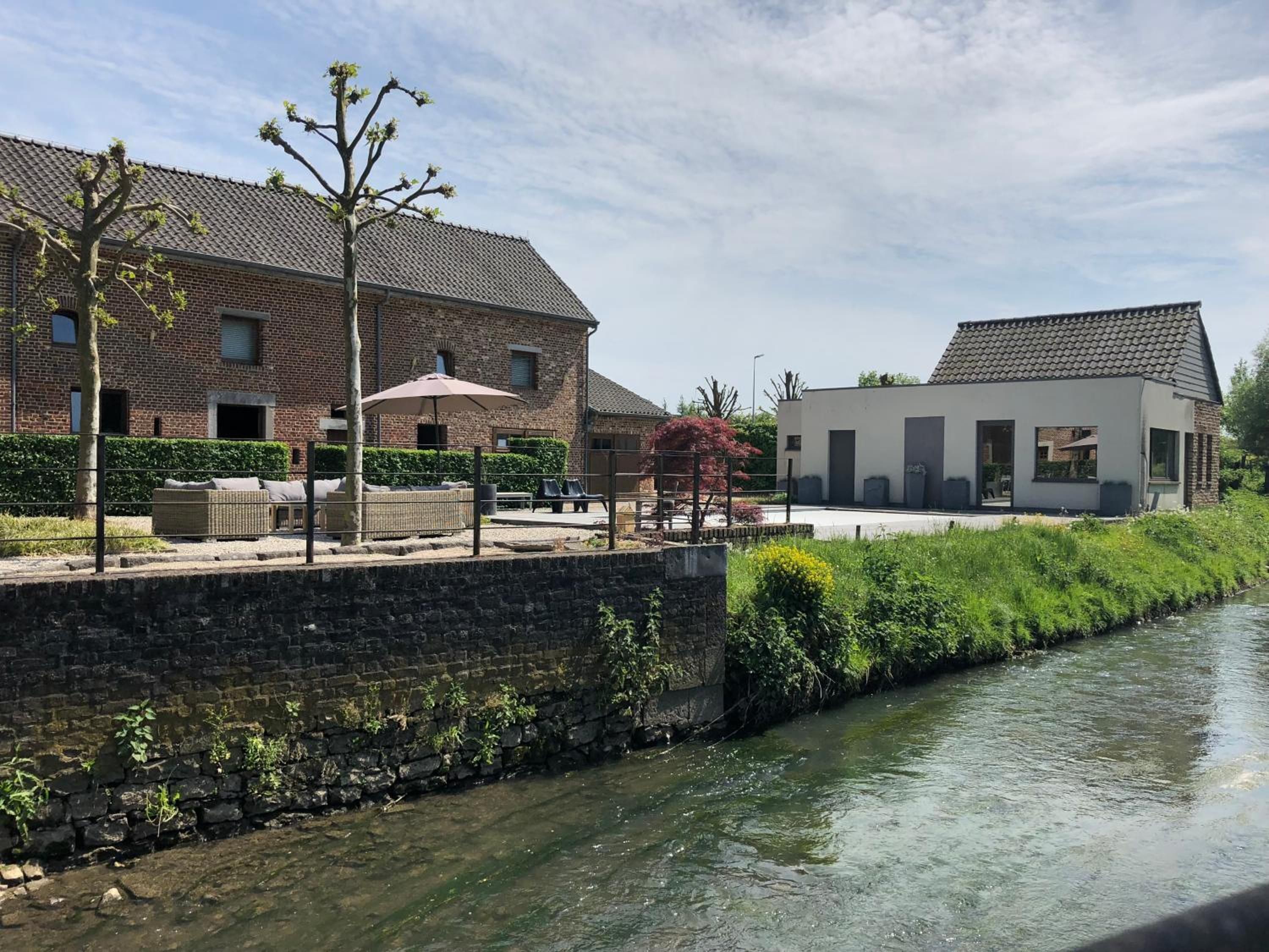 Een pand aan de rivier met een bakstenen gebouw, een modern bouwwerk en een stenen muur.