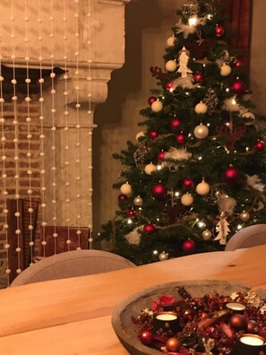 A Christmas tree with ornaments and lights, a candle holder with candles, and a draped curtain.