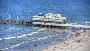 A pier extending into the water with a restaurant named "EAT AT JOE'S" on a boat.