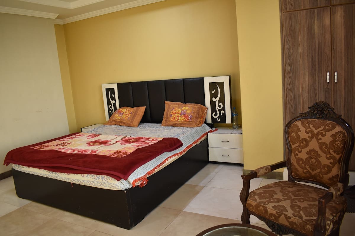 Une chambre à coucher comprenant un lit, des tables de chevet, une chaise et une armoire.