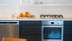 A modern kitchen with a dishwasher, oven, and gas stove. There are fruits on the counter and a roll of paper towels.