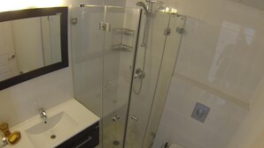 A bathroom with a glass-enclosed shower, a white sink, and a toilet.