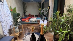 Een gezellig buitenzitgedeelte met houten meubels, een tafel met wijnglazen en een fles wijn.