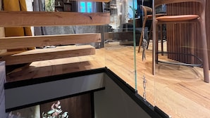 Een modern interieur met houten balken, een glazen wand en een zithoek met een stoel en tafel.