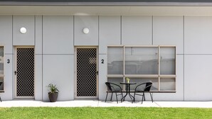 Un bâtiment moderne avec des portes numérotées, une grande fenêtre et des places assises à l’extérieur.
