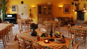 A dining area with multiple tables and chairs, a piano, and a fireplace. - Agriturismo Walden (Ficulle)