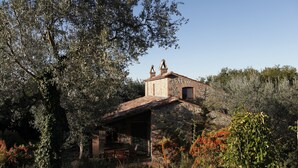 A rustic stone building with a sloped roof, a chimney, and a small porch with outdoor seating. - Agriturismo Walden (Ficulle)