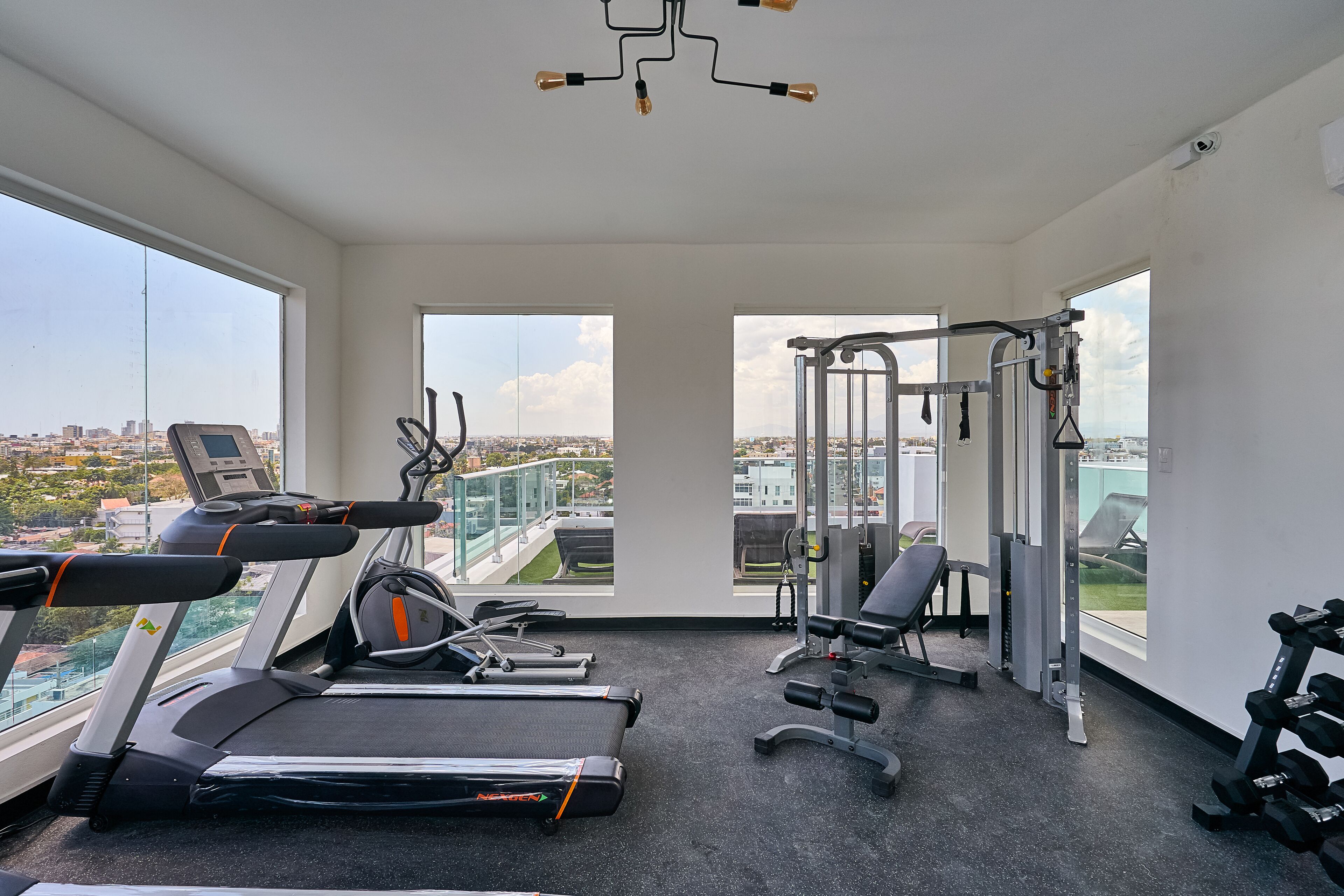 Un gimnasio con cintas de correr, máquinas de pesas y mancuernas.