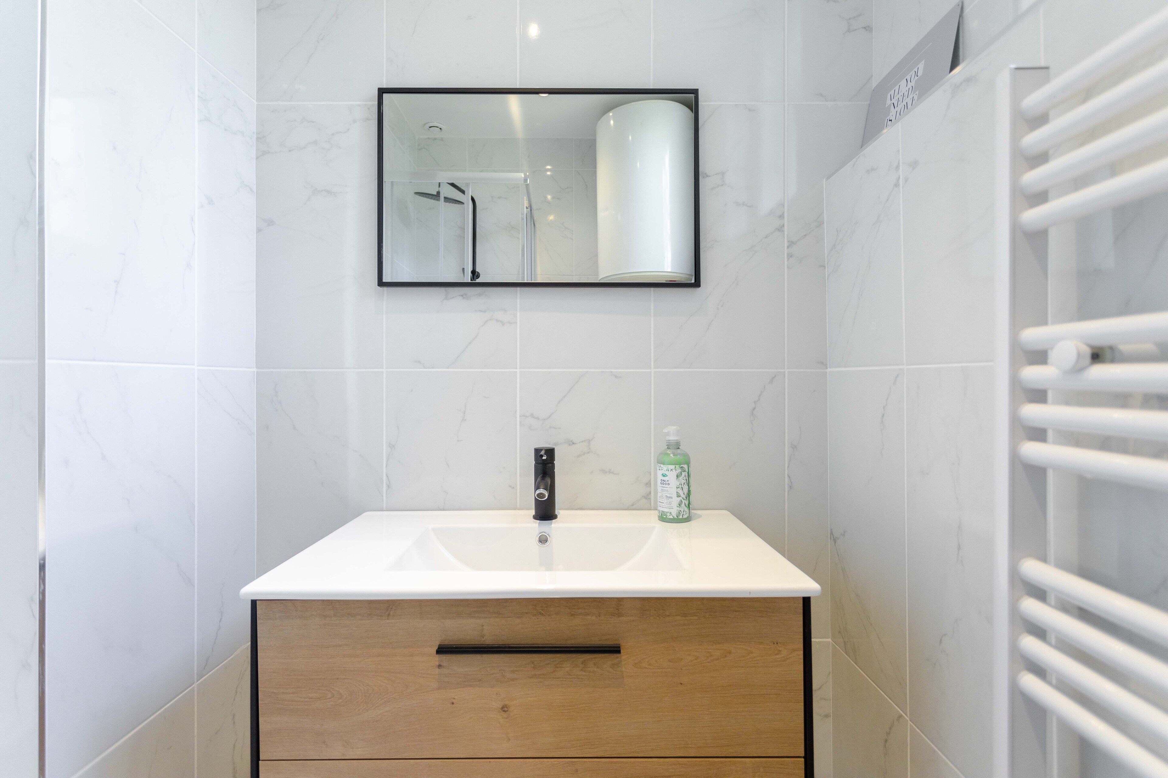 Une salle de bain avec un lavabo blanc, un miroir et un porte-serviettes.
