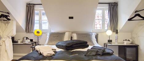 A bedroom with a large bed, two bedside tables, a wardrobe, and a window with curtains.