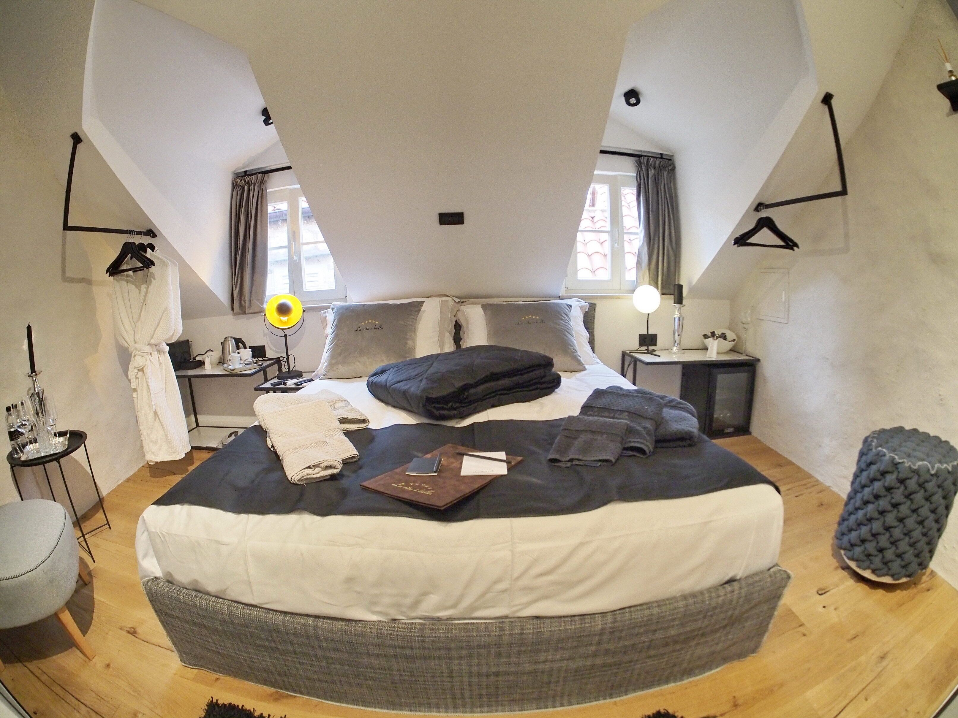 A spacious bedroom with a large bed, bedside tables, a desk, and a chair.