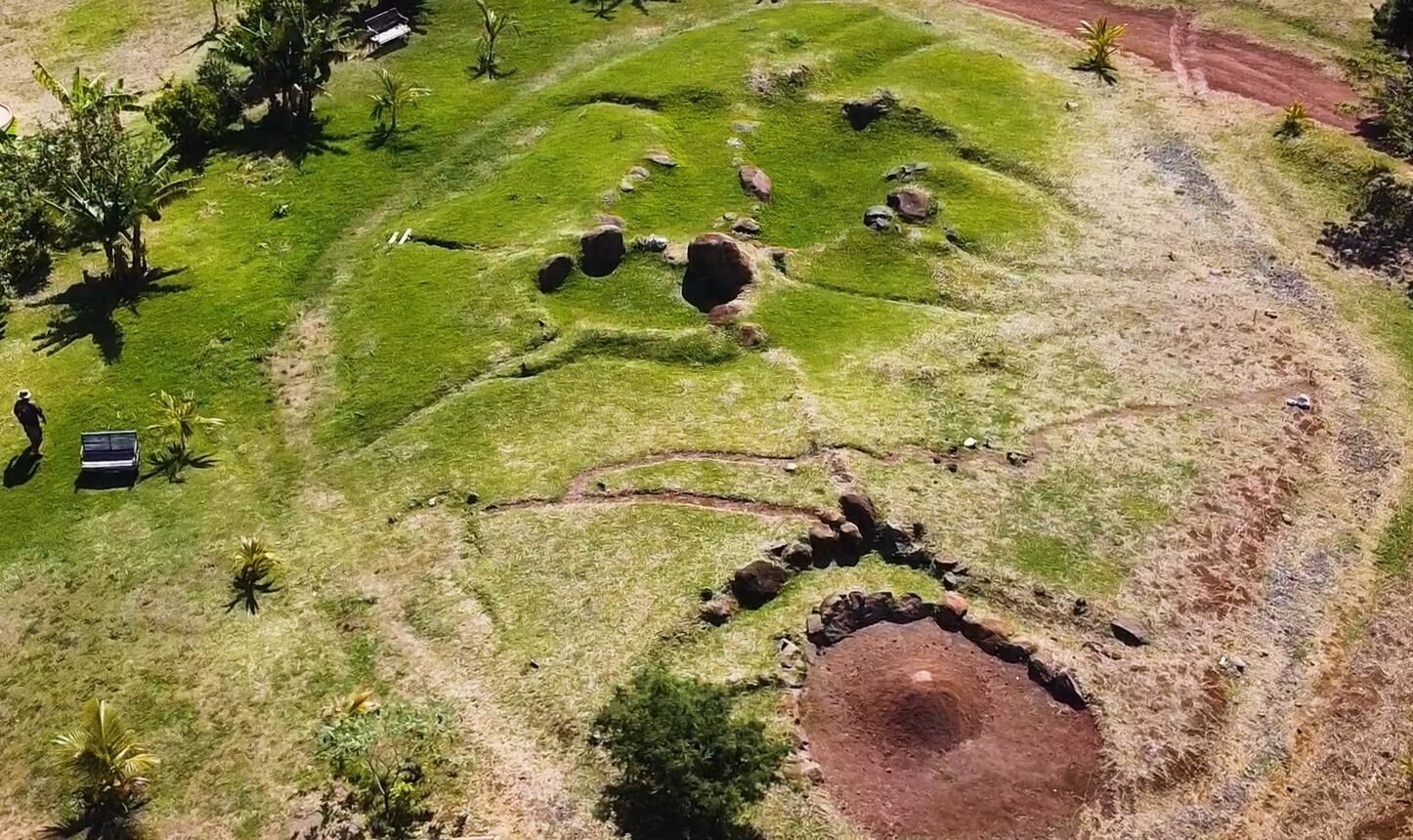 An aerial view of a grassy area with several circular mounds and a dirt path.