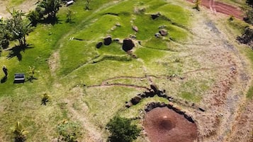 An aerial view of a grassy area with several circular mounds and a dirt path.